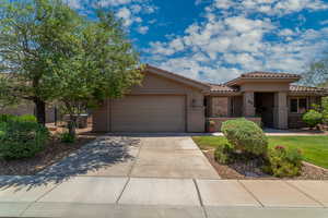 View of front facade with a garage, a tiled roof, stucco siding, and driveway