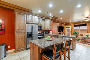Kitchen featuring stainless steel appliances, a peninsula, light tile patterned floors, ceiling fan, and a breakfast bar area