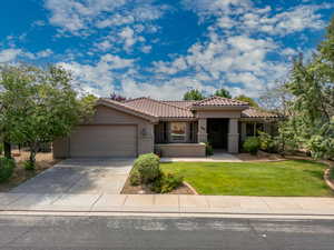 Mediterranean / spanish home with a garage, stucco siding, a tile roof, concrete driveway, and a front lawn