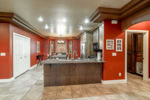 Kitchen featuring black microwave, freestanding refrigerator, a peninsula, dark stone countertops, and light tile patterned floors