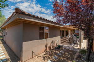 View of side of property with a patio, stucco siding, and a tiled roof