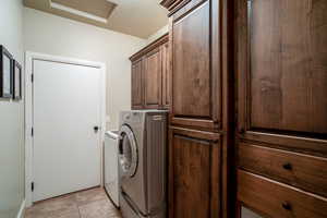 Laundry room with cabinet space, attic access, independent washer and dryer, and light tile patterned floors