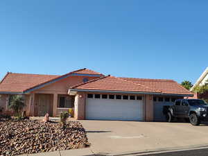 Ranch-style home with concrete driveway, an attached garage, stucco siding, and a tiled roof