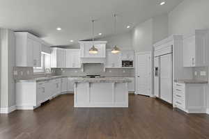 Kitchen with built in appliances, white cabinets, tasteful backsplash, dark wood-type flooring, and recessed lighting