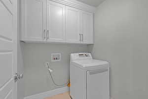 Laundry area with washer / clothes dryer, cabinet space, and light tile patterned floors
