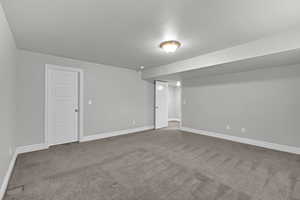 Finished below grade area with dark colored carpet and a textured ceiling