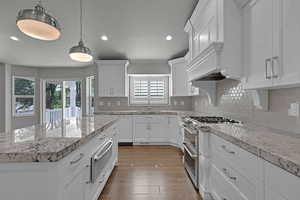 Kitchen with double oven range, a warming drawer, recessed lighting, white cabinets, and dark wood-style floors