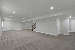 Finished basement featuring carpet floors, recessed lighting, and stairs