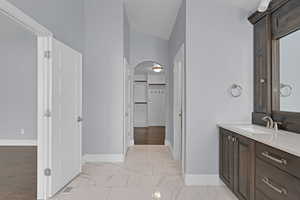 Bathroom featuring vanity, a spacious closet, and marble look tiles