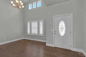 Foyer featuring dark wood-style flooring, a chandelier, and high vaulted ceiling