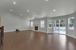 Unfurnished living room with a glass covered fireplace, recessed lighting, and dark wood finished floors