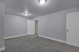 Spare room featuring a textured ceiling and dark colored carpet