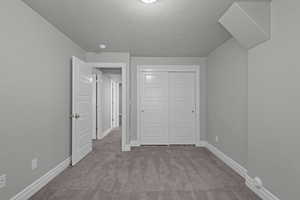 Unfurnished bedroom featuring carpet, a textured ceiling, and a closet