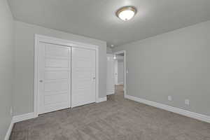 Unfurnished bedroom with carpet flooring, a closet, and a textured ceiling