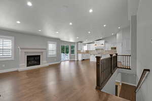 Unfurnished living room with recessed lighting, a glass covered fireplace, dark wood-type flooring, and vaulted ceiling