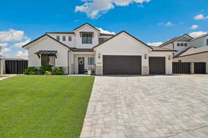 Modern farmhouse with decorative driveway, a garage, and stone siding