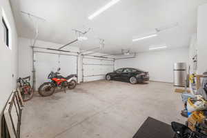 Garage featuring freestanding refrigerator and a garage door opener