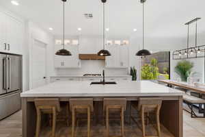 Kitchen featuring high end fridge, tasteful backsplash, recessed lighting, glass insert cabinets, and a kitchen breakfast bar