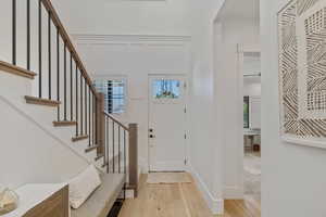 Entrance foyer with light wood finished floors, stairway, and a decorative wall