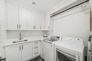 Laundry room featuring separate washer and dryer, cabinet space, and dark tile patterned floors