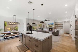 Kitchen featuring stainless steel appliances, a ceiling fan, light wood-type flooring, a fireplace, and recessed lighting