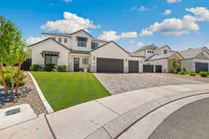 Modern inspired farmhouse with decorative driveway, an attached garage, and stone siding