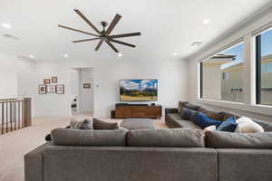 Carpeted living area featuring ceiling fan and recessed lighting