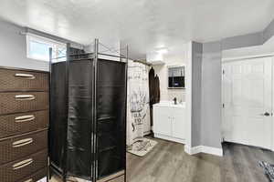 Full bathroom with vanity, wood finished floors, curtained shower, and a textured ceiling