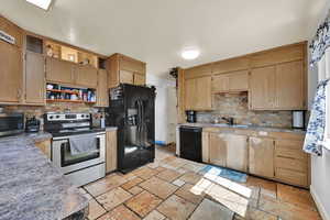 Kitchen featuring black appliances, open shelves, tasteful backsplash, stone tile floors, and light countertops