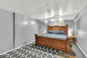 Bedroom featuring dark carpet and a textured ceiling