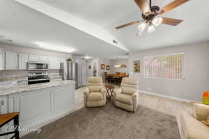 Living area with light wood-style floors, vaulted ceiling, and a ceiling fan
