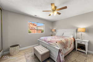 Bedroom with wood finished floors, ceiling fan, and a textured ceiling