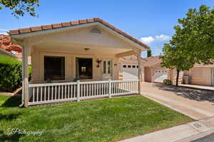 View of front of home with an attached garage, concrete driveway, a front lawn, and a tiled roof