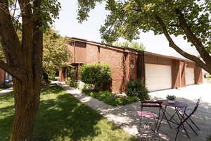 View of front of property featuring driveway, brick siding, an attached garage, and a front yard