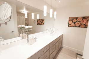 Bathroom featuring tile patterned flooring, double vanity, and a shower with curtain