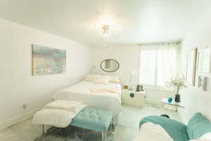 Tiled bedroom featuring baseboards and a chandelier