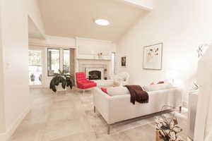 Living area featuring a high end fireplace, light tile patterned flooring, and high vaulted ceiling