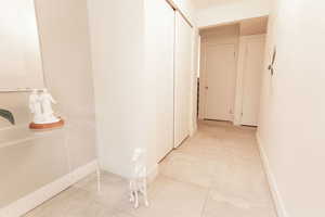 Corridor featuring light tile patterned floors and baseboards