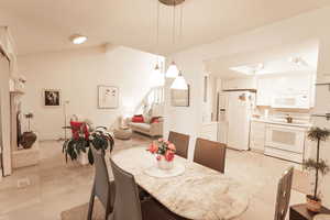 Dining area featuring light tile patterned floors, lofted ceiling, and stairs