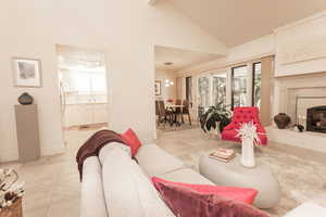 Living room with plenty of natural light, a fireplace, light tile patterned floors, and high vaulted ceiling