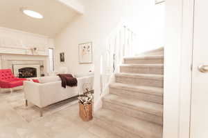 Stairs featuring beam ceiling, a high end fireplace, tile patterned floors, and high vaulted ceiling