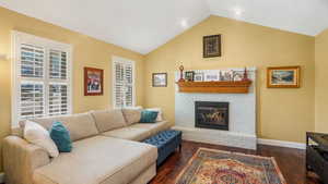 Living area featuring lofted ceiling, dark wood finished floors, and a fireplace