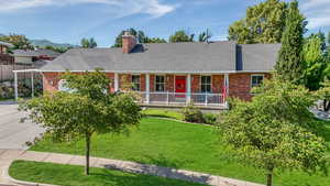 View of front facade with brick siding, a chimney, and a shingled roof