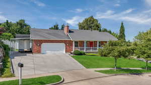 Ranch-style home with brick siding, a porch, a front lawn, and an attached garage