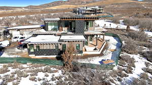 Snow covered property featuring a mountain view, a pergola, a patio, and board and batten siding