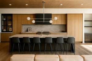 Kitchen with modern cabinets, light wood finished floors, a breakfast bar area, recessed lighting, and a large island with sink