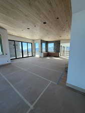 Unfurnished room with wooden ceiling and concrete flooring