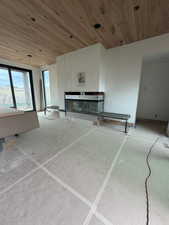 Unfurnished living room with wood ceiling and a glass covered fireplace