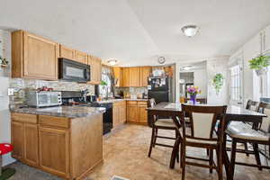 Kitchen with black appliances, decorative backsplash, vaulted ceiling, and a textured ceiling