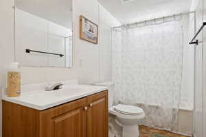 Full bath featuring a textured ceiling, vanity, and shower / tub combo